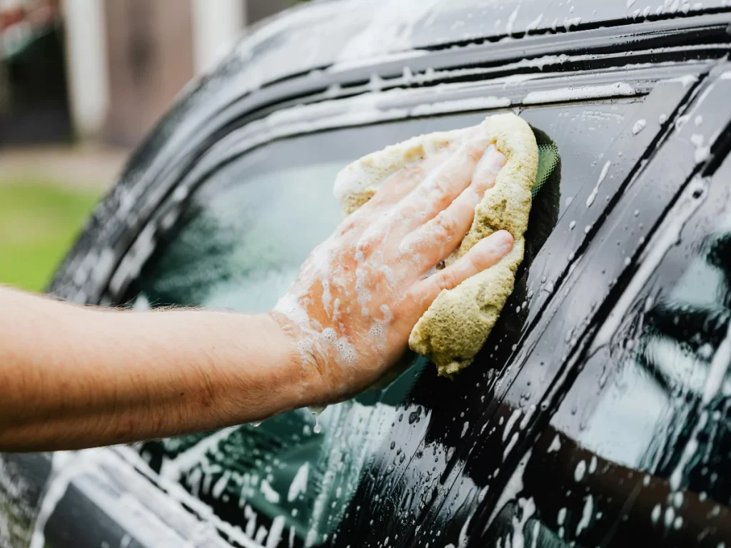 Auto Wash Membership in Cinco Ranch Equestrian Village hand washing the car windows with a soapy sponge.