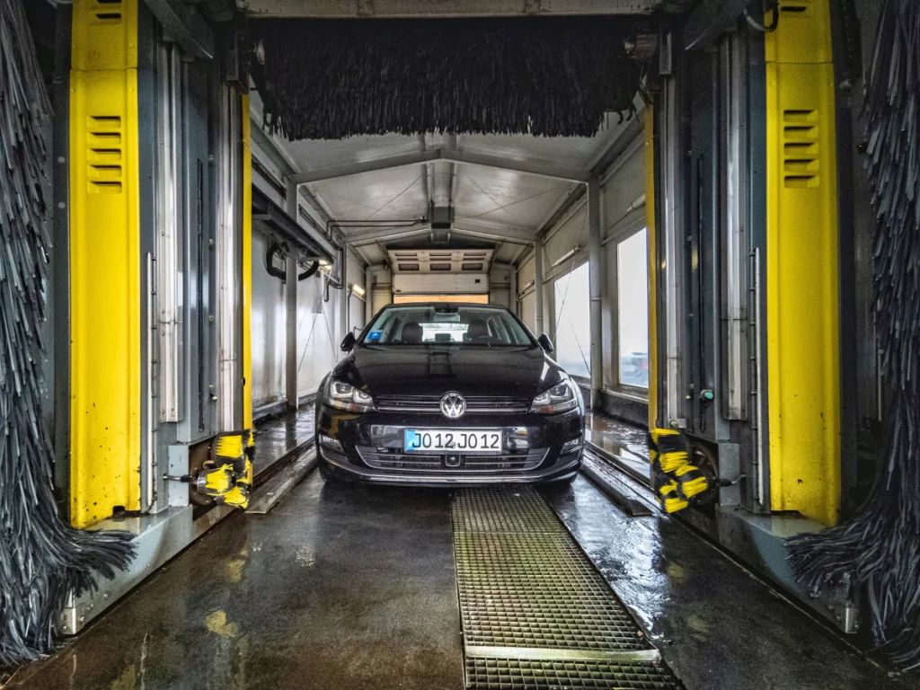 Kelliwood Greens Monthly Car Wash Plan car undergoing an automated wash in a modern car wash tunnel with yellow brushes.