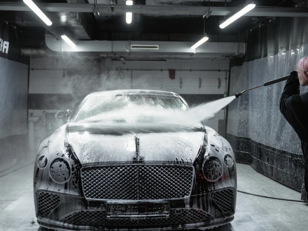 Car Cleaning Service in Lakeforest Of Kelliwood detailed view of a car being cleaned with foam and water in a modern facility.