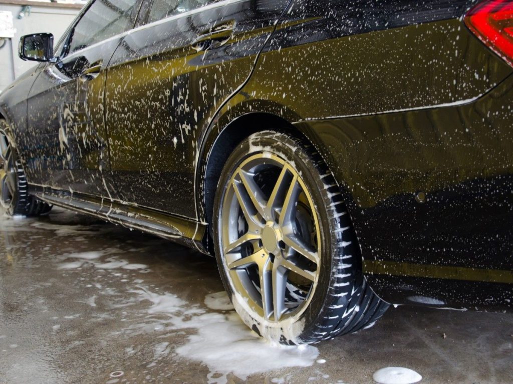 Car wash membership deals with Kelliwood Park, a close-up of a dark, soapy car with clean wheels and tires.