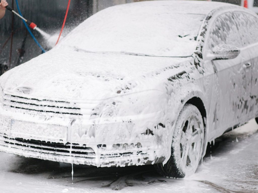 Car wash subscription Cinco Ranch Equestrian Village, a car completely covered in a thick layer of white soap foam at a car wash.