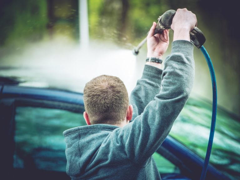 Cheap Car Wash Katy TX, person using a high-pressure water sprayer on a car