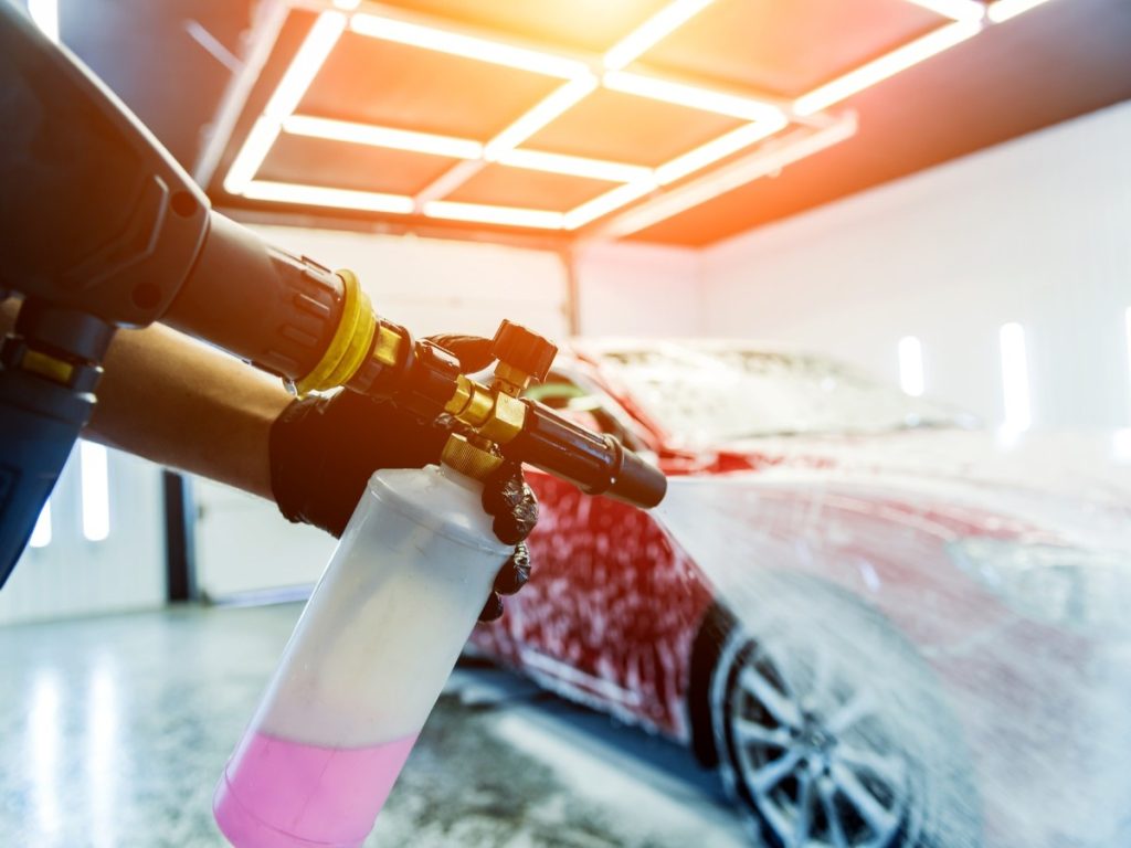 A red car being covered in foam by a professional, highlighting our Local car wash membership in Cinco Ranch Equestrian Village.