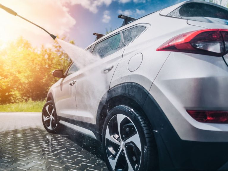 White SUV being washed with high-pressure water under sunny sky at Affordable Car Wash Katy TX.