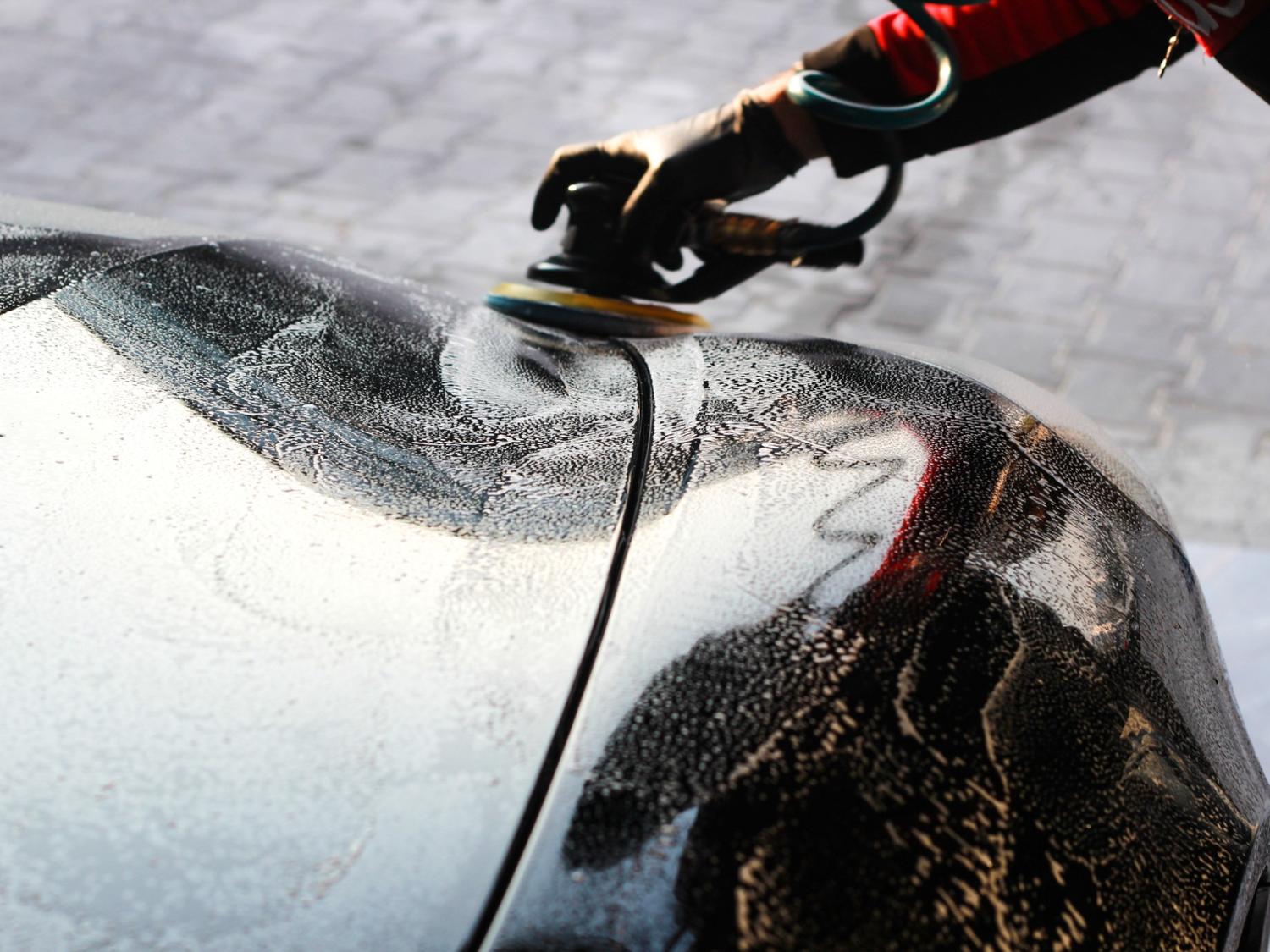 Hand polishing wet, soapy car with a tool at Drive-Thru Car Wash Katy TX.