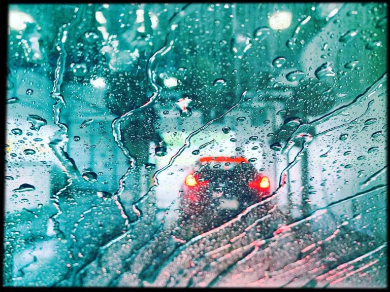 Rain-covered windshield with water droplets and traffic - car wash membership Katy TX weather guide