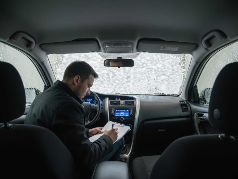 Man writing in a snowy car interior, promoting best car wash membership Katy TX services for clean vehicles in all weather.
