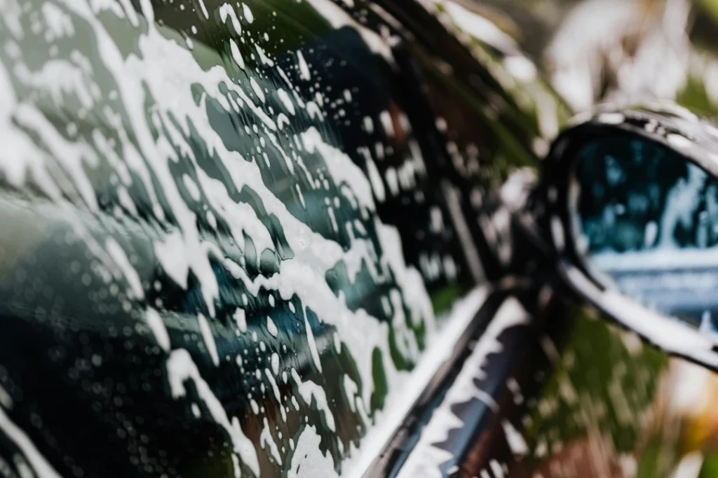 Car side mirror and window covered in thick foam, detailing service at the Best Car Wash in Katy TX location.