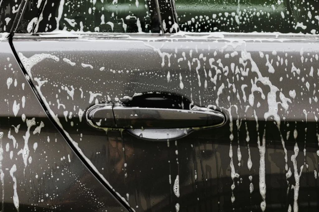 Close-up of car door handle covered in rich white soap suds, showcasing the Best Car Wash in Katy TX quality.