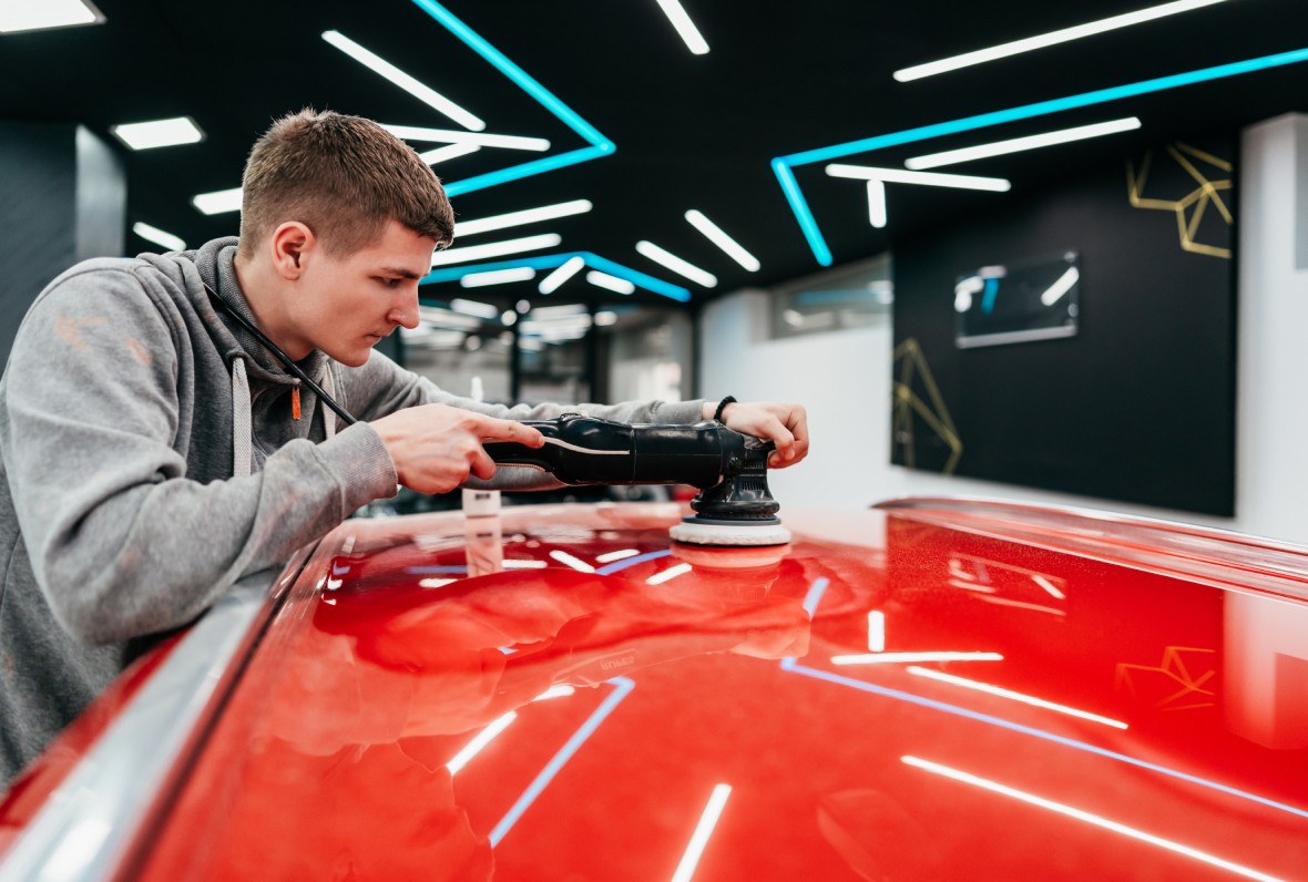 Professional detailer using an orbital buffer for paint correction at the Best Car Wash in Katy TX facility.